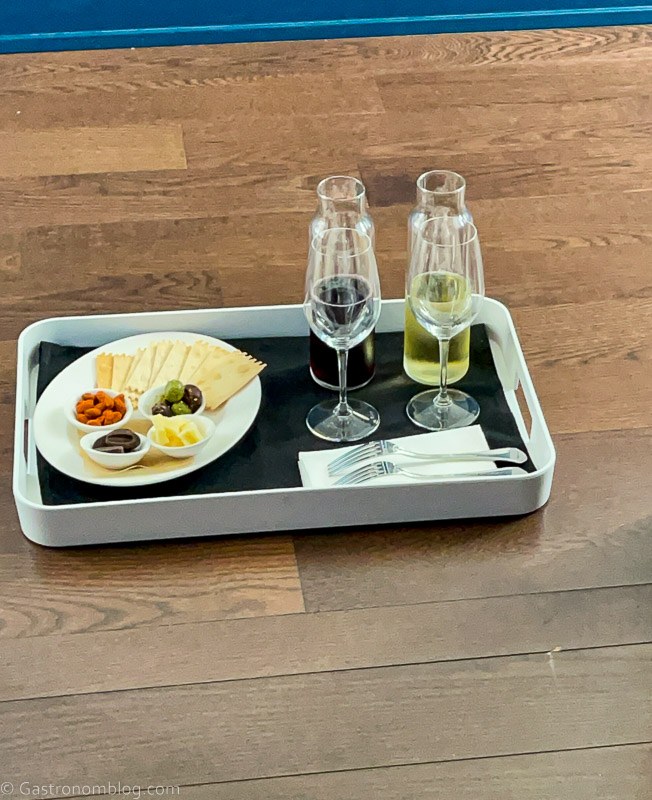 White tray with black napkin and wine in carafes with glasses and antipasti on white plate