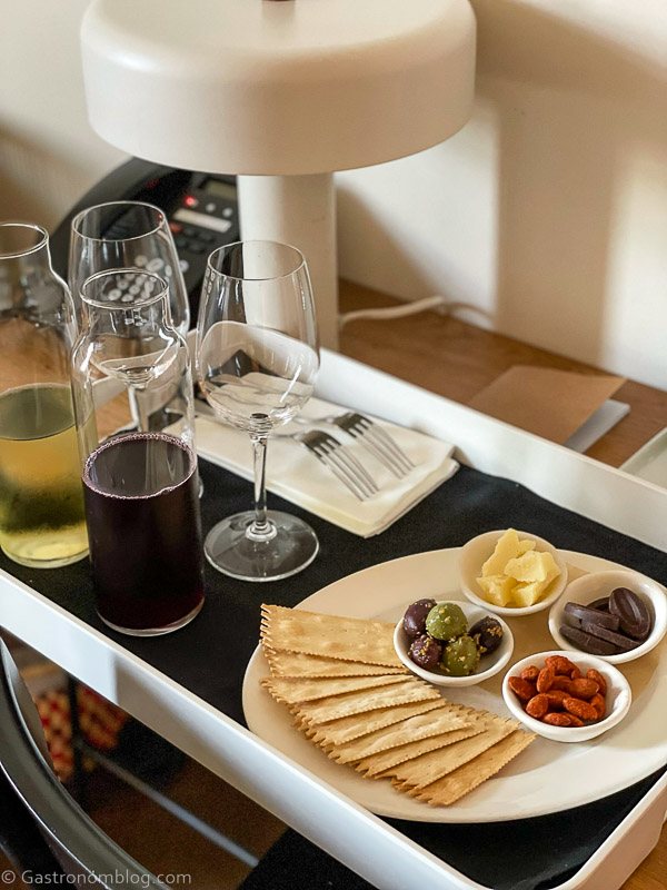 White tray with black napkin and wine in carafes with glasses and antipasti on white plate
