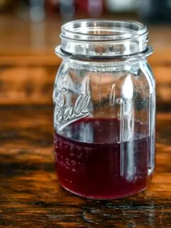 Purple Blackberry syrup recipe in glass jar on wooden table