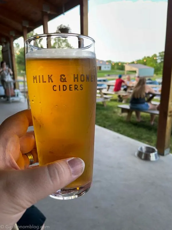 Hand holding glass of golden cider at Milk and Honey Ciders