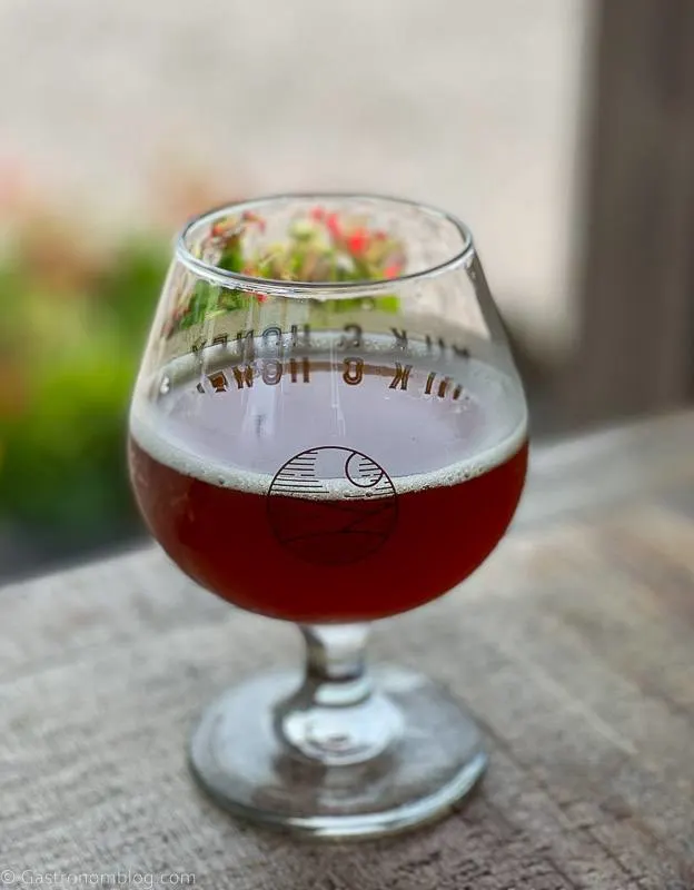 Glass of dark brown cider on table at Milk and Honey Ciders