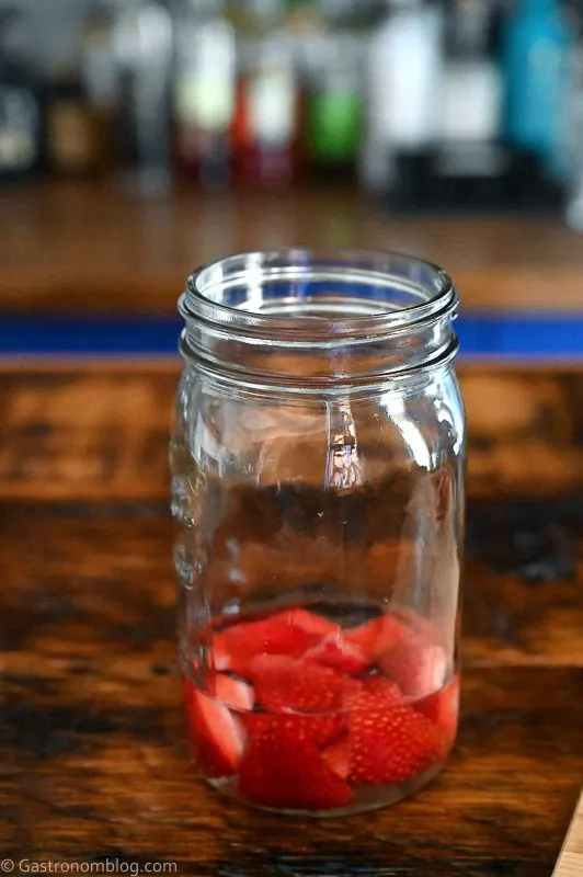 Strawberries in liquid in jar on wood table