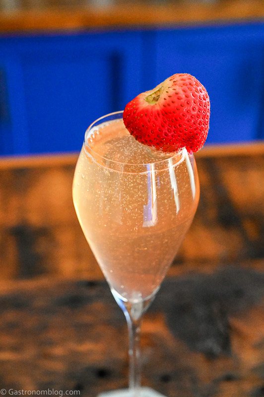 Strawberry Mimosa, Pink bubbly cocktail in flute with strawberry garnish on the side