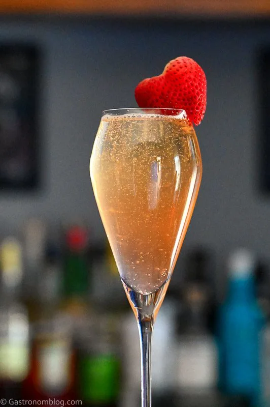 Strawberry Mimosa, Pink bubbly cocktail in flute with strawberry garnish on the side