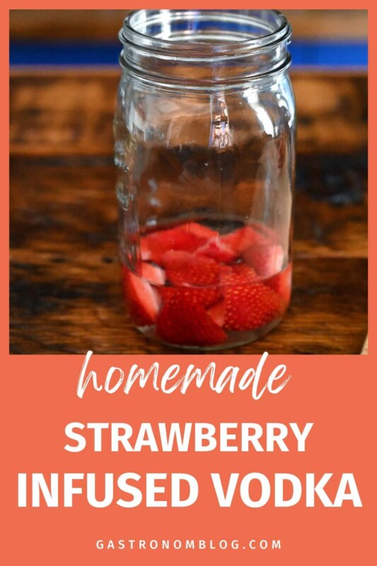 Strawberries in liquid in jar on wood table
