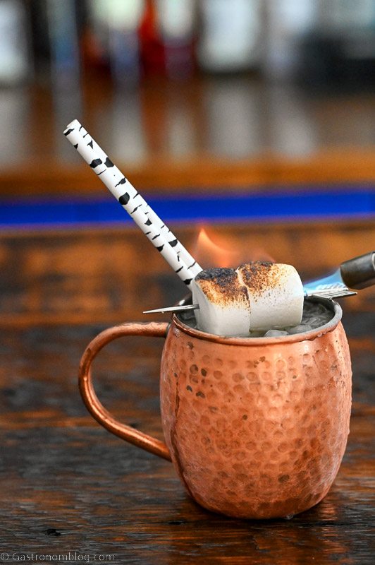 Cocktail in a copper mug with birch tree straws and marshmallow garnish