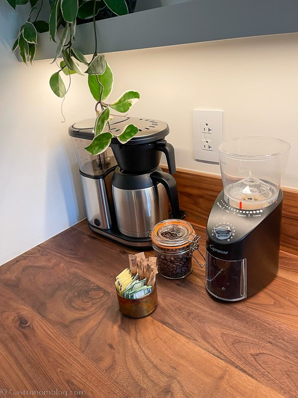 Coffee pot and coffee grinder with coffee items on wood counter