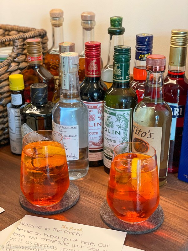 Aperol spritzes welcome cocktail at The Pinch Charleston, bottles from wet bar behind