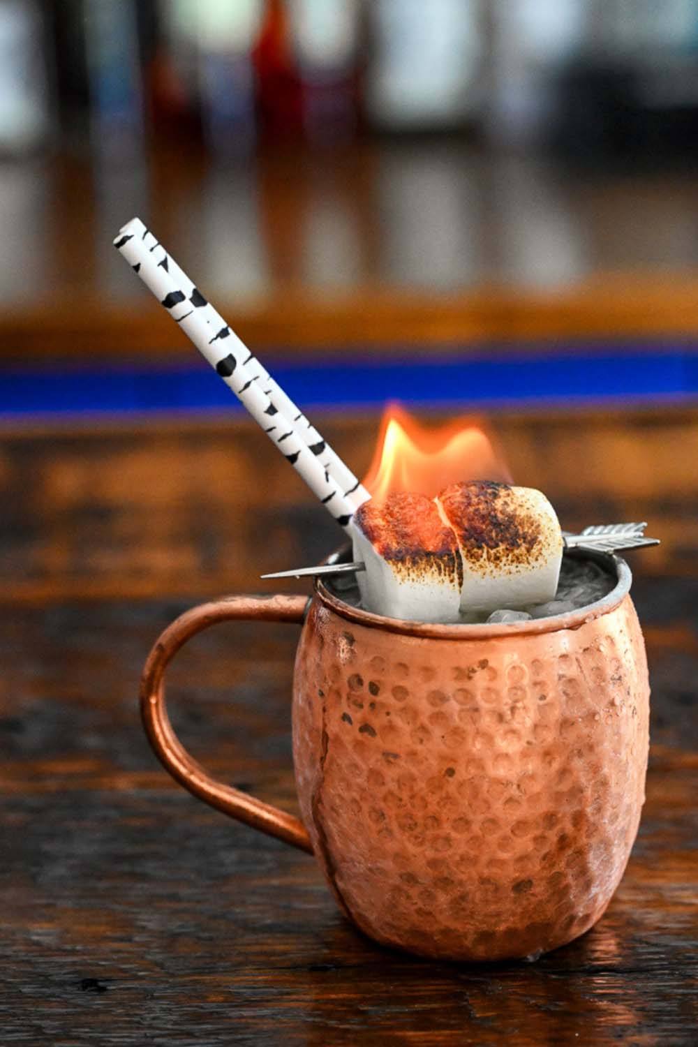 Cocktail in a copper mug with birch tree straws and marshmallow garnish