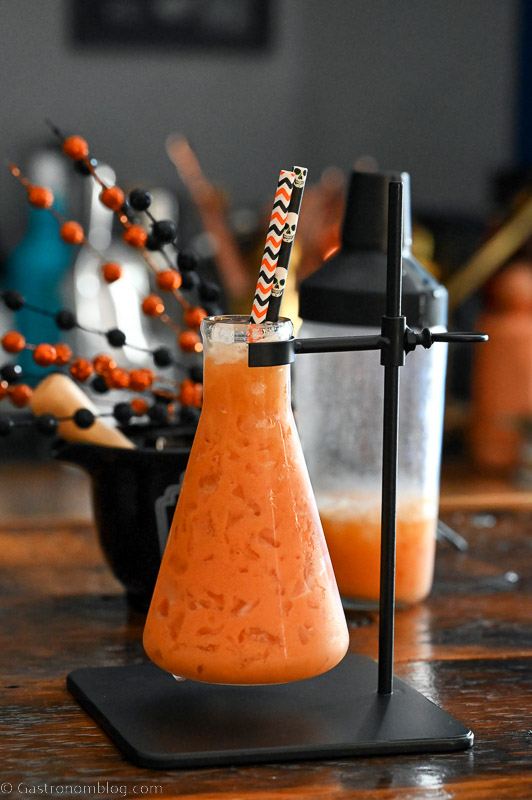 Orange Pumpkin Cocktail in a beaker as a glass with Halloween straws