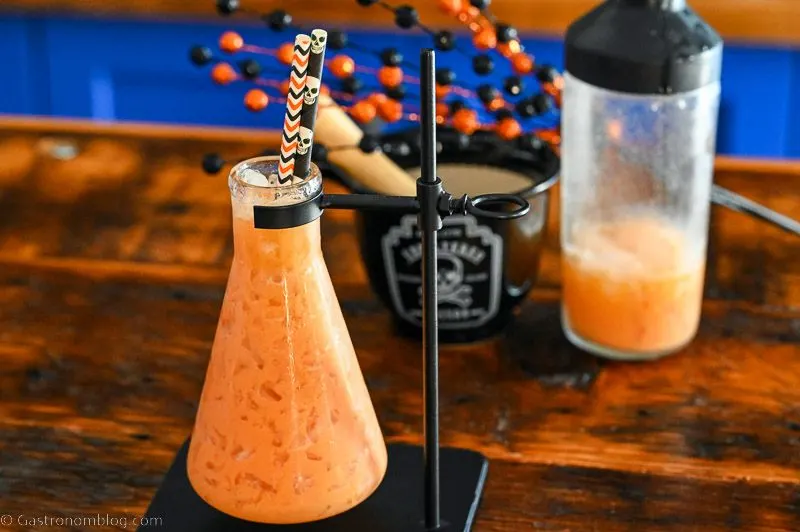 Orange Pumpkin Cocktail in a beaker as a glass with Halloween straws