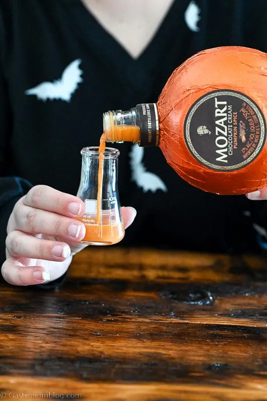 orange pumpkin liqueur being poured into a small beaker