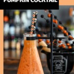 Orange cocktail in beaker, bottle of pumpkin liqueur behind