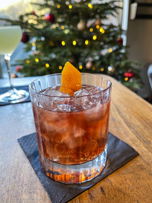 cocktail in rocks glass on table, Christmas tree behind