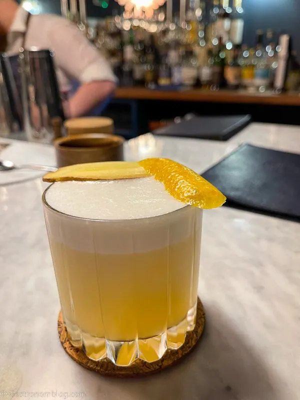 yellow cocktail with foam and lemon peel on white marble bar top at Killiecrankie House