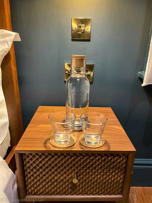 Water carafe and glasses on side table, blue wall