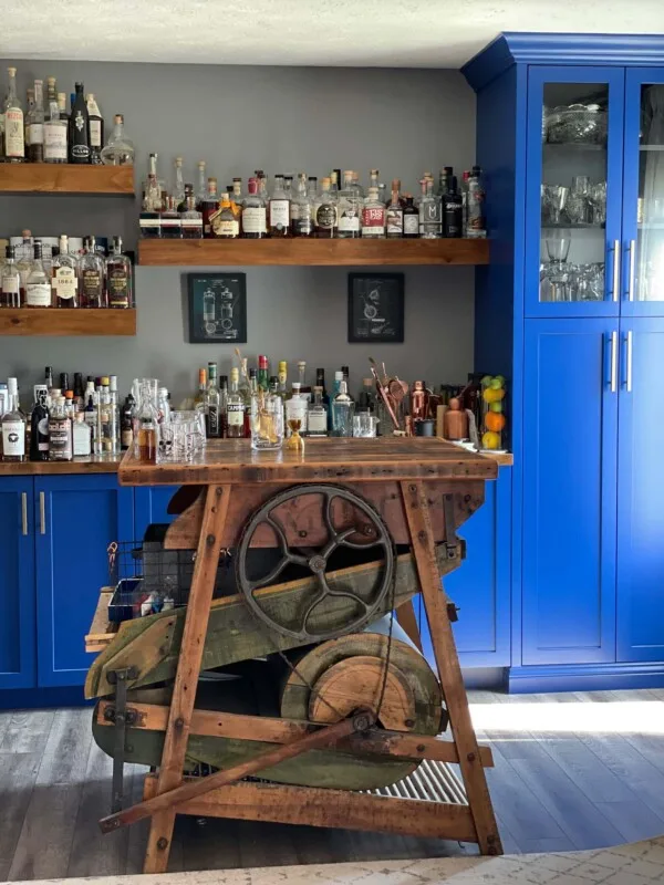 Home bar with blue cabinets and bottles of alcohol on shelves