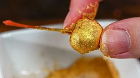 Hand holding a gold glitter cherry