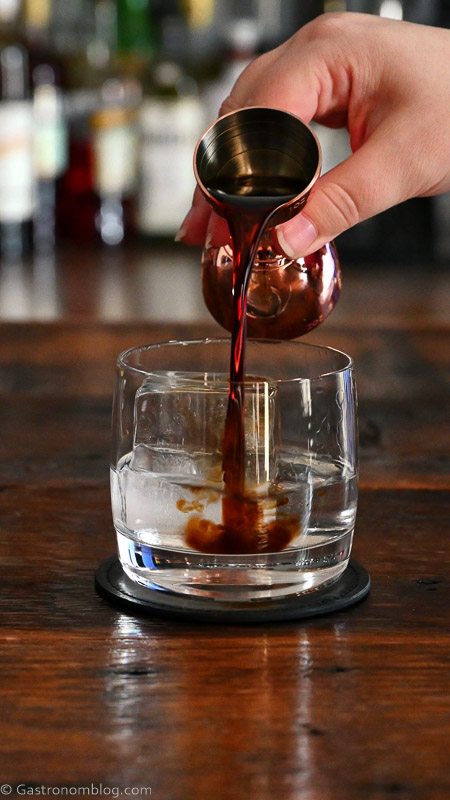 Kahlua being poured into rocks glass from jigger