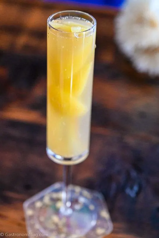 orange juice ice cubes being placed in champagne flute for Easter Mimosas