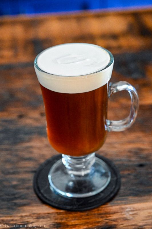 Brown Irish Coffee Cocktail in glass mug with white cream layer on top