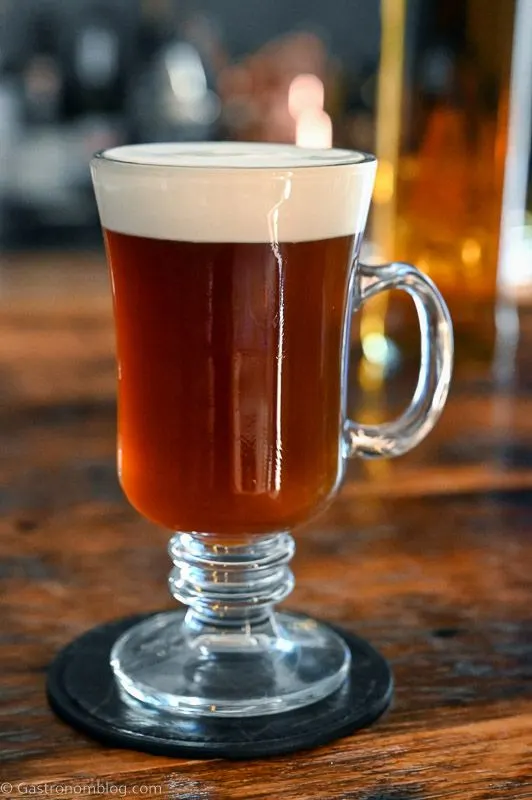 Brown Irish Coffee Cocktail in glass mug with white cream layer on top