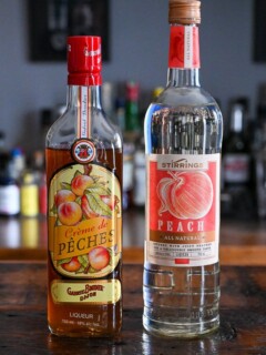 2 bottles of peach liqueur on a wooden table