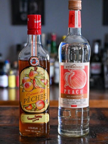 2 bottles of peach liqueur on a wooden table