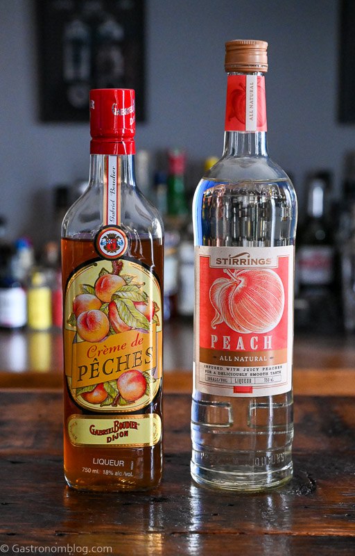 2 bottles of peach liqueur on a wooden table