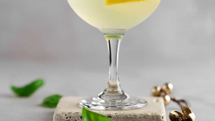 Yellow cocktail in coupe with basil leaves