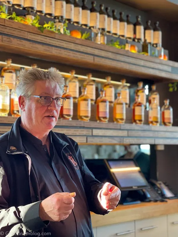 Tour guide with whisky bottles behind at Lindores Abbey Distillery