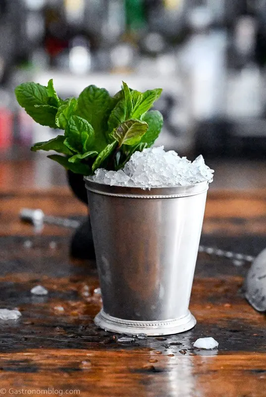 Mint Julep in a silver cup with crushed ice and mint leaves on wooden table