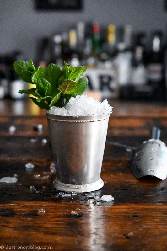 Mint Julep in a silver cup with crushed ice and mint leaves on wooden table