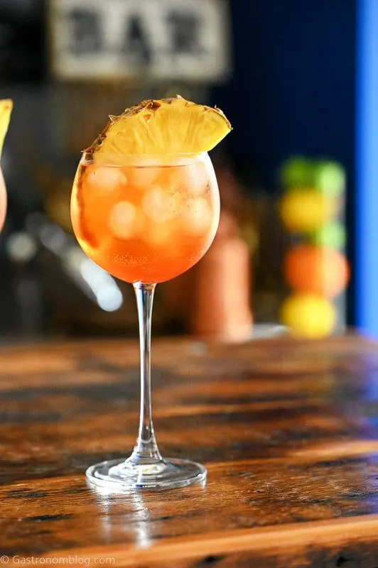 Orange cocktails in wine glass with ice cubes and pineapple slice