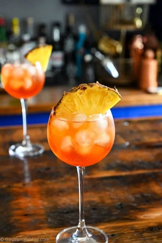 Orange cocktails in wine glass with ice cubes and pineapple slice