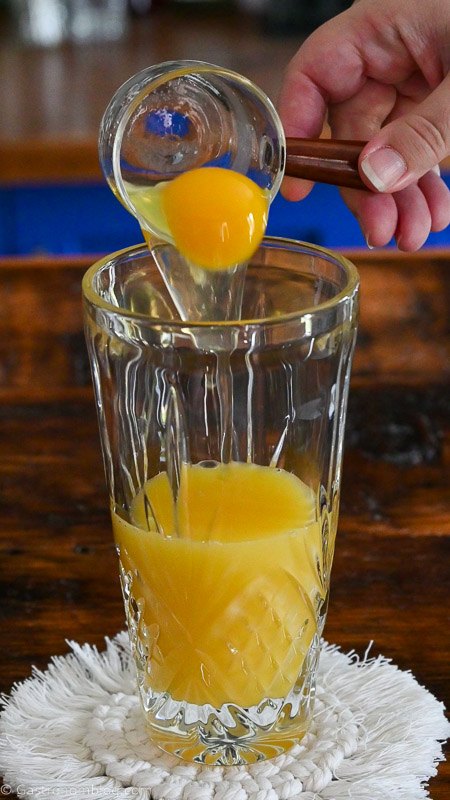 Egg being poured into a glass shaker.