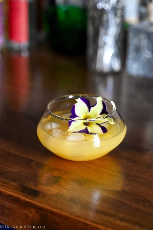 Yellow Pineapple Wine Punch in punch cup with edible flower