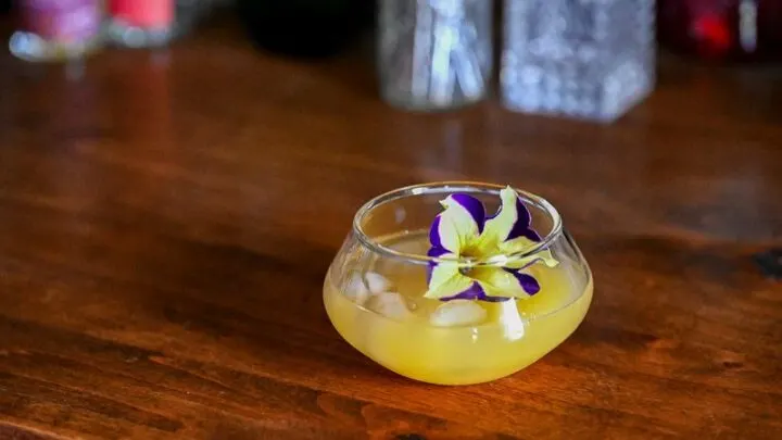 Yellow Pineapple Wine Punch in punch cup with edible flower