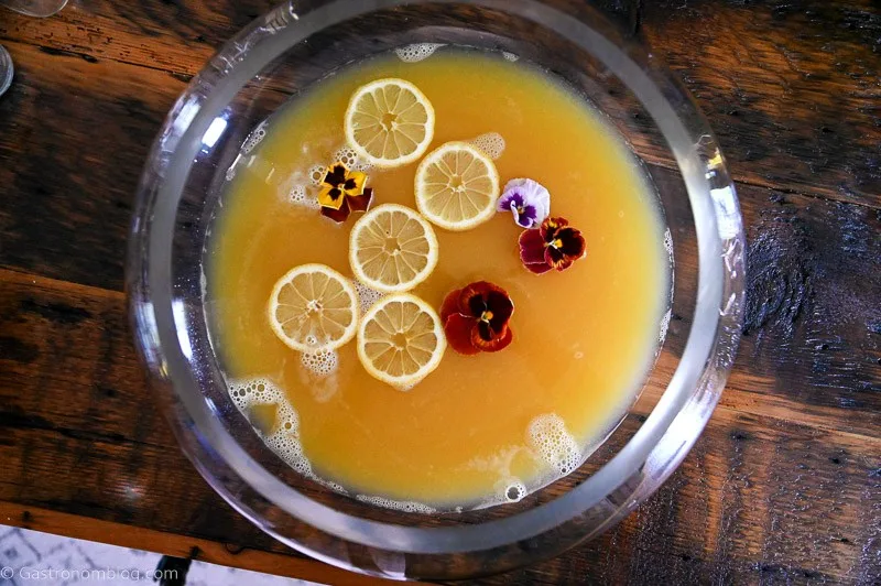 Yellow Pineapple Wine Punch in punch bowl with edible flowers and citrus slices