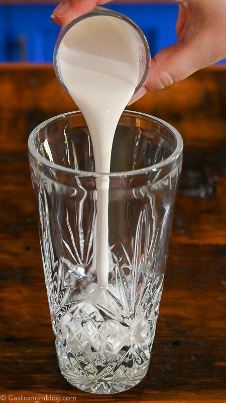 coconut cream being poured into glass cocktail shaker