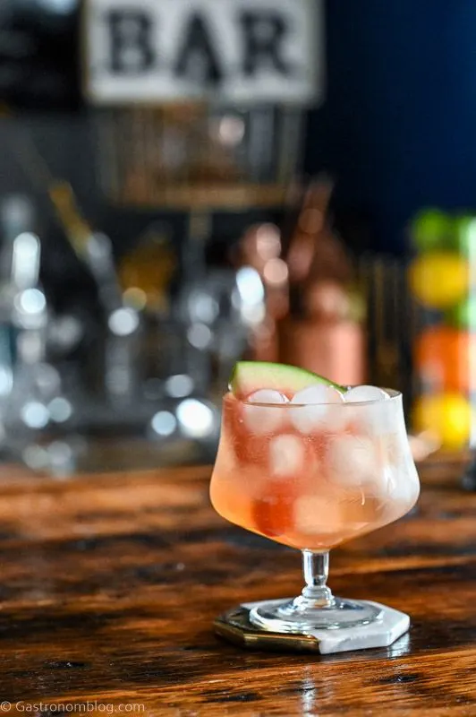 Pink cocktail, Watermelon Aperol Spritz in a low glass with stem on wood table. Ice cubes in glass with watermelon slice