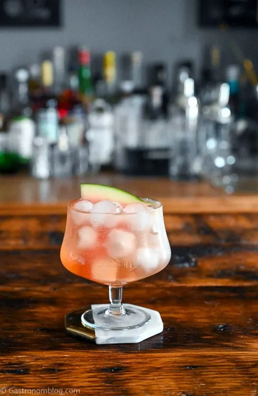 Pink cocktail, Watermelon Aperol Spritz in a low glass with stem on wood table. Ice cubes in glass with watermelon slice