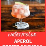 Pink cocktail, Watermelon Aperol Spritz in a low glass with stem on wood table. Ice cubes in glass with watermelon slice