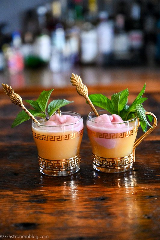 orange pineapple orange punch in gold trimmed punch cups topped with raspberry sherbet and mint leaves