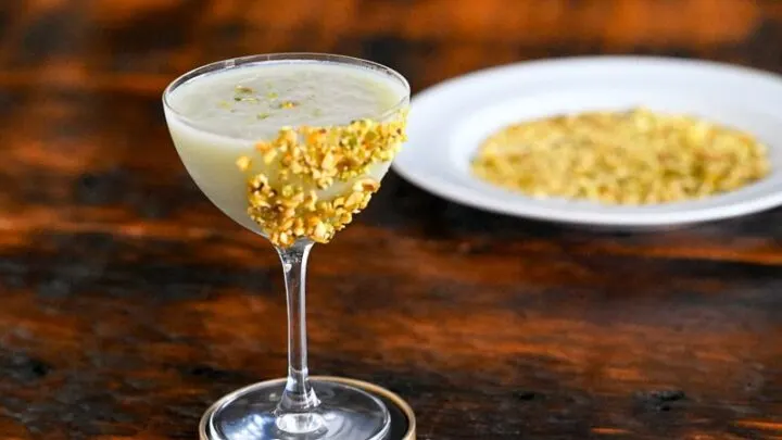 Light green Pistachio Martini Recipe in a coupe with pistachios on rim