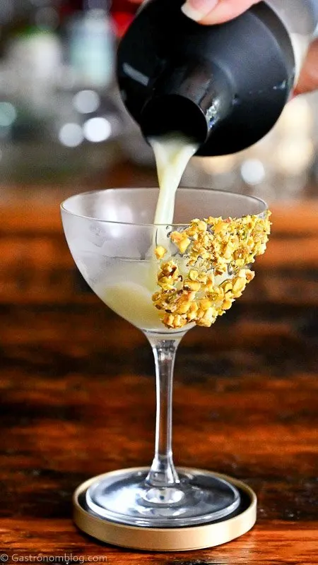 Light green Pistachio Martini Recipe in a coupe with pistachios on rim