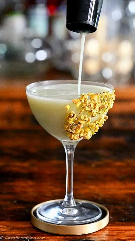 Light green Pistachio Martini Recipe in a coupe with pistachios on rim