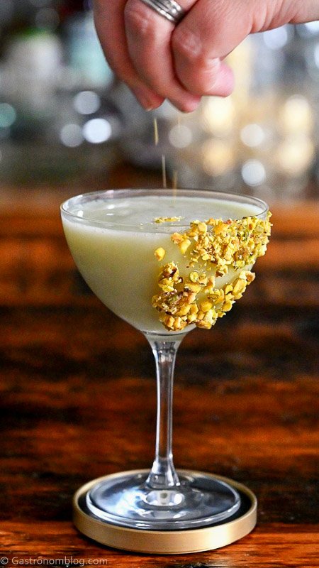 Light green Pistachio Martini Recipe in a coupe with pistachios on rim