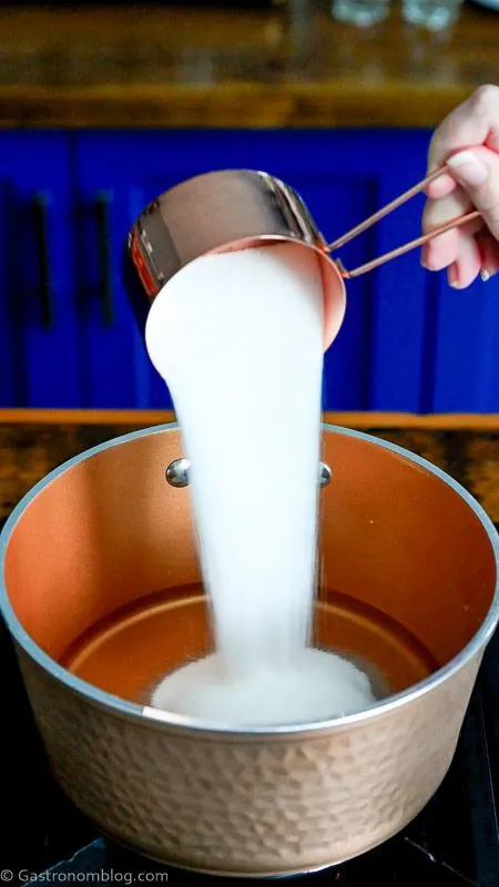 sugar being poured into copper saucepan