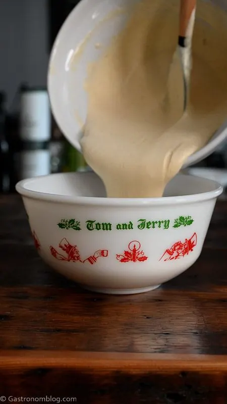 spiced batter being poured into bowl for a Tom and Jerry Drink
